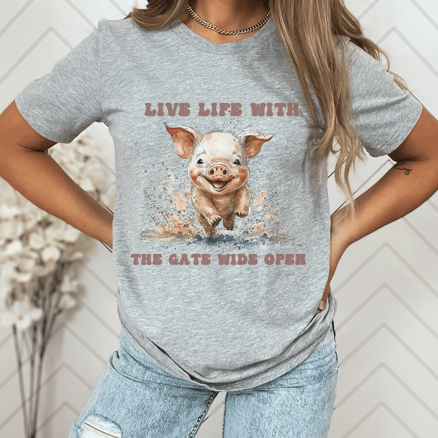 Introducing our Cute Piggy Tee, featuring a charming little pig happily running through the mud. With the inspirational message "Live life with the gate wide open," this farm animal-inspired t-shirt is perfect for anyone who loves country life. Made from high-quality materials, this pink pig shirt is both comfortable and stylish. Order now and show your love for adorable farm animals with our Piggy Shirt!