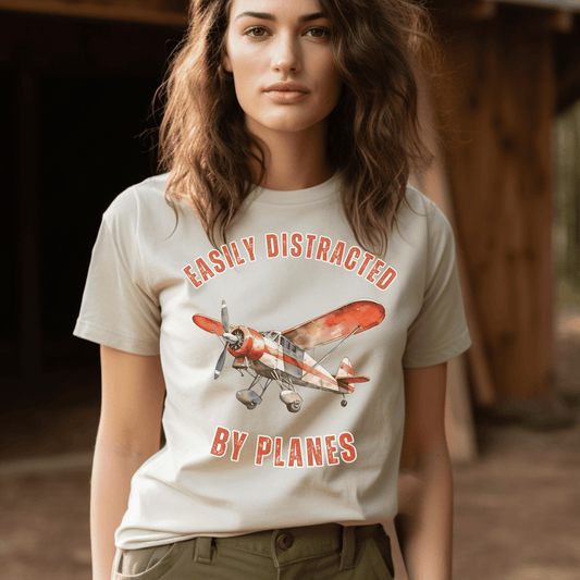 Vintage Plane illustration accompanied by the cheeky saying, easily distracted by planes. Made from high-quality, soft fabric, this comfortable t-shirt allows you to show off your love for planes in style