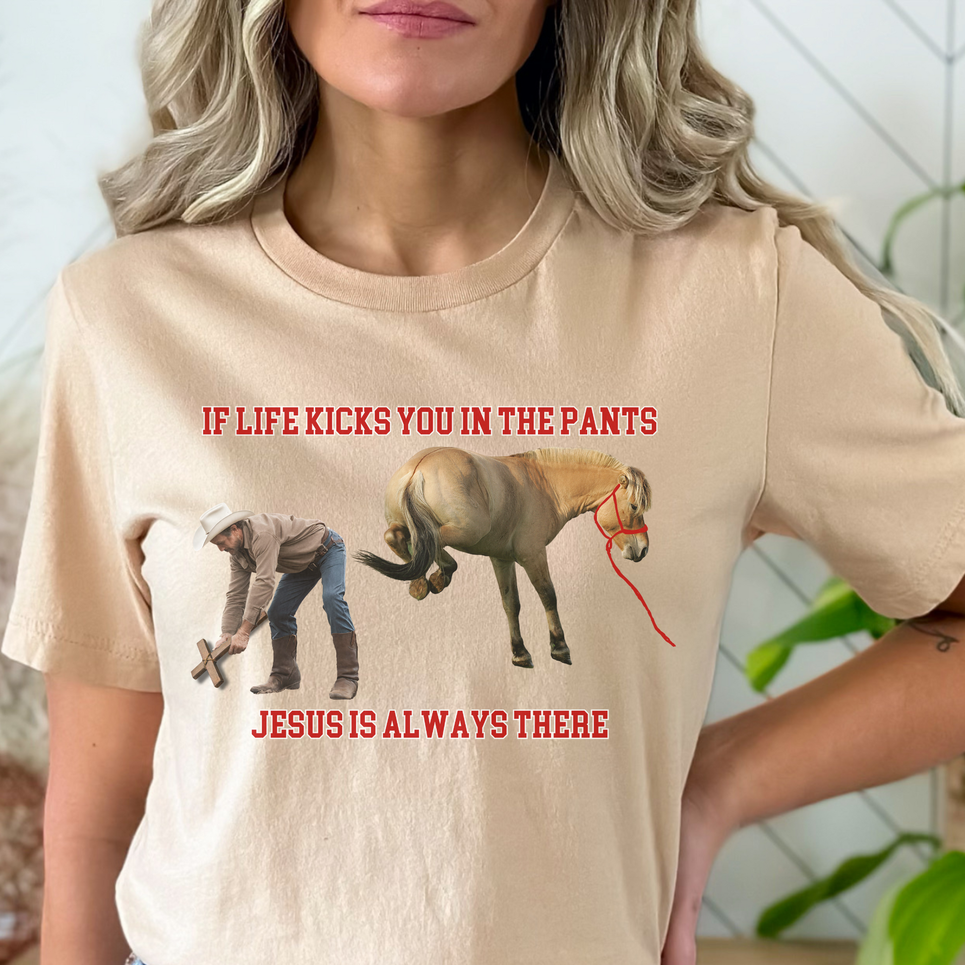 Crew Neck western t-shirt, If Life kicks you in the pants Jesus is always there. with the picture of a cowboy bending over holding a cross getting kicked by a horse.