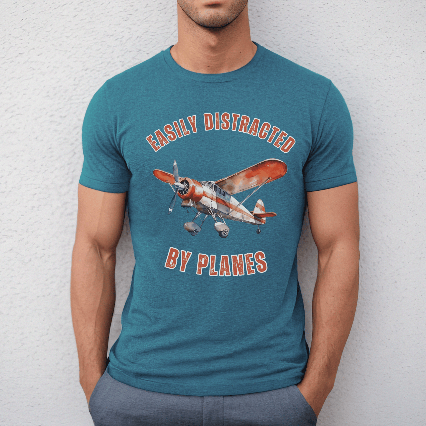 Vintage Plane illustration accompanied by the cheeky saying, easily distracted by planes. Made from high-quality, soft fabric, this comfortable t-shirt allows you to show off your love for planes in style