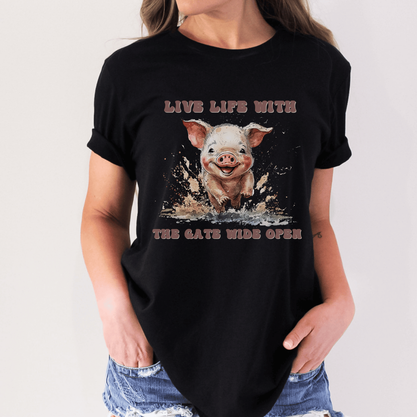 Introducing our Cute Piggy Tee, featuring a charming little pig happily running through the mud. With the inspirational message "Live life with the gate wide open," this farm animal-inspired t-shirt is perfect for anyone who loves country life. Made from high-quality materials, this pink pig shirt is both comfortable and stylish. Order now and show your love for adorable farm animals with our Piggy Shirt!