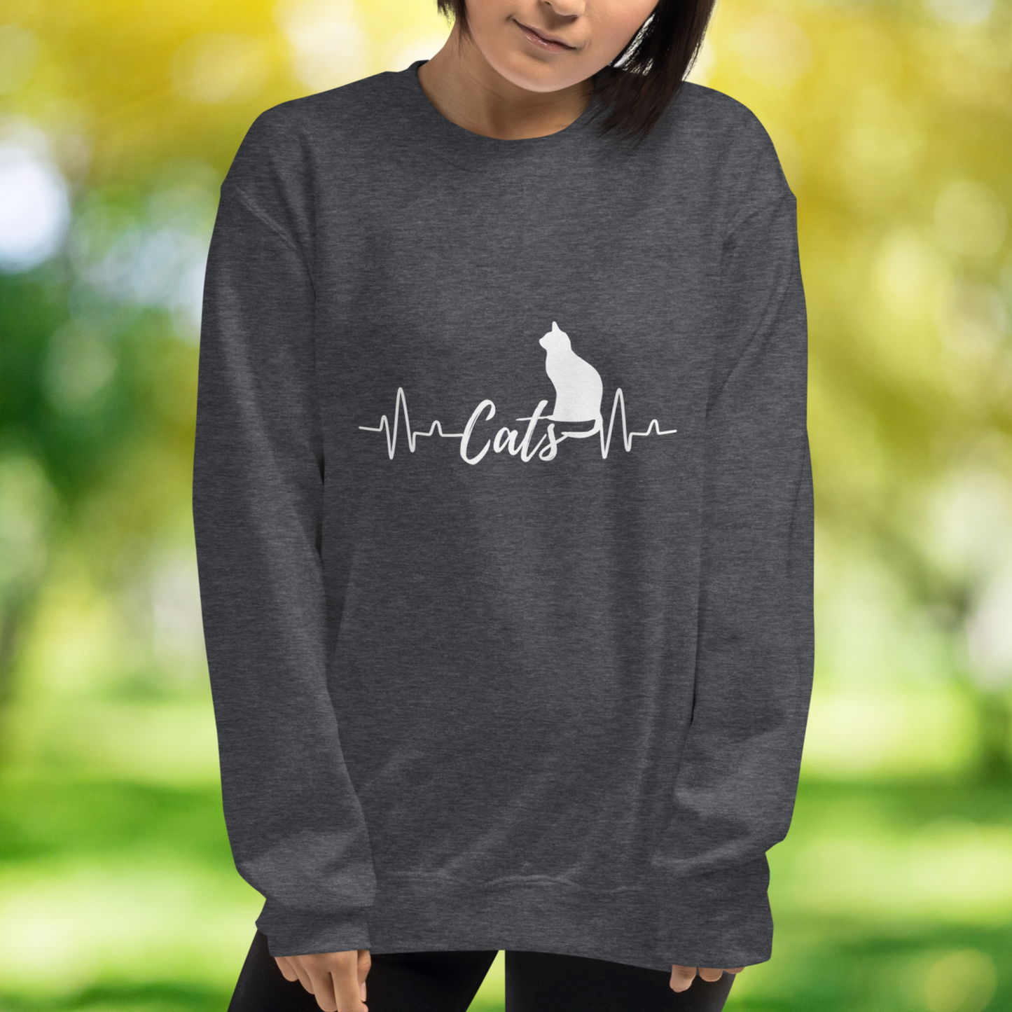 Sitting cat silhouette with a heartbeat with the word Cats in the middle of the heartbeat. The design is all white on a Dark Heather Greysweatshirt.