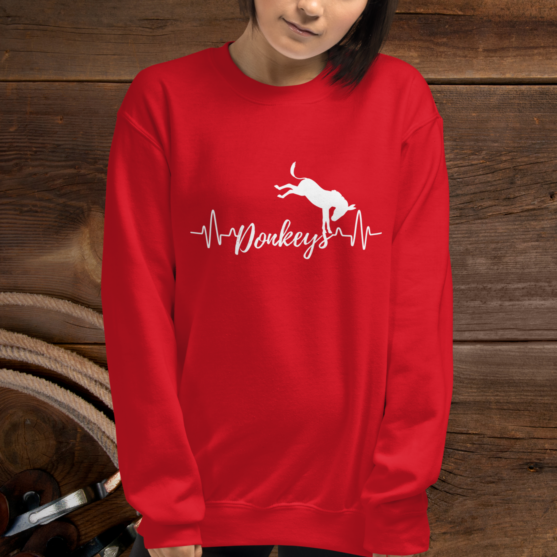 Red crew neck sweatshirt with a heart beat design with  the word Donkeys in the middle of the heartbeat, with a silhouette of a bucking donkey above it.