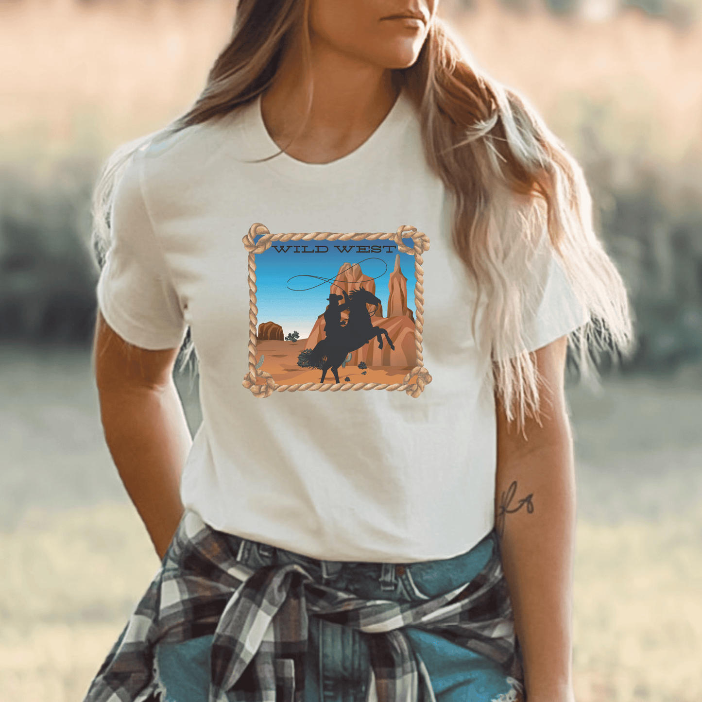 Soft cream colored tee with a wild west desert scene  with a rearing horse and cowboy